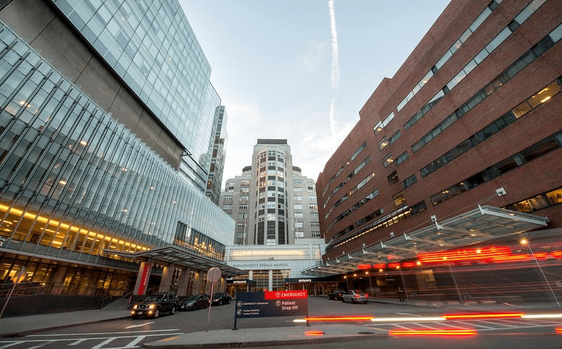 The entrance to Mass General Hospital glows with streaks of moving lights at dusk.